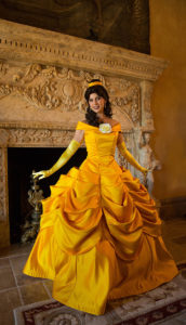 A Princess Belle performer reading a book to children at a party.