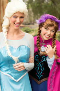 Elsa and Anna princess performers singing and interacting with children at a party.