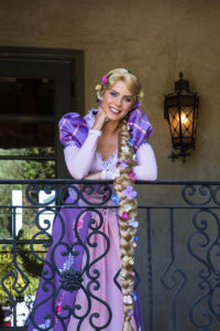 Rapunzel princess performer assisting kids with a colorful painting craft at a party.