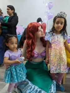 A group of kids posing with a princess character at a decorated photo booth.