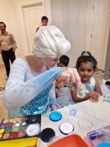 Elsa-themed birthday decorations with blue balloons, snowflake garlands, and frosty table settings.