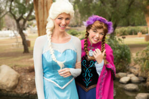 Elsa and Anna princess performers singing with excited children at a birthday party