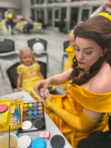 Belle-inspired princess reading a book in an enchanting library setting.